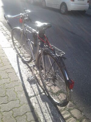 vélo debout appuyé sur un trottoir grâce à la manivelle gauche